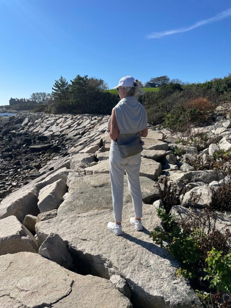 Frau steht auf Felsen am Meer und schaut in die Weite — bereit für einen neuen Anfang