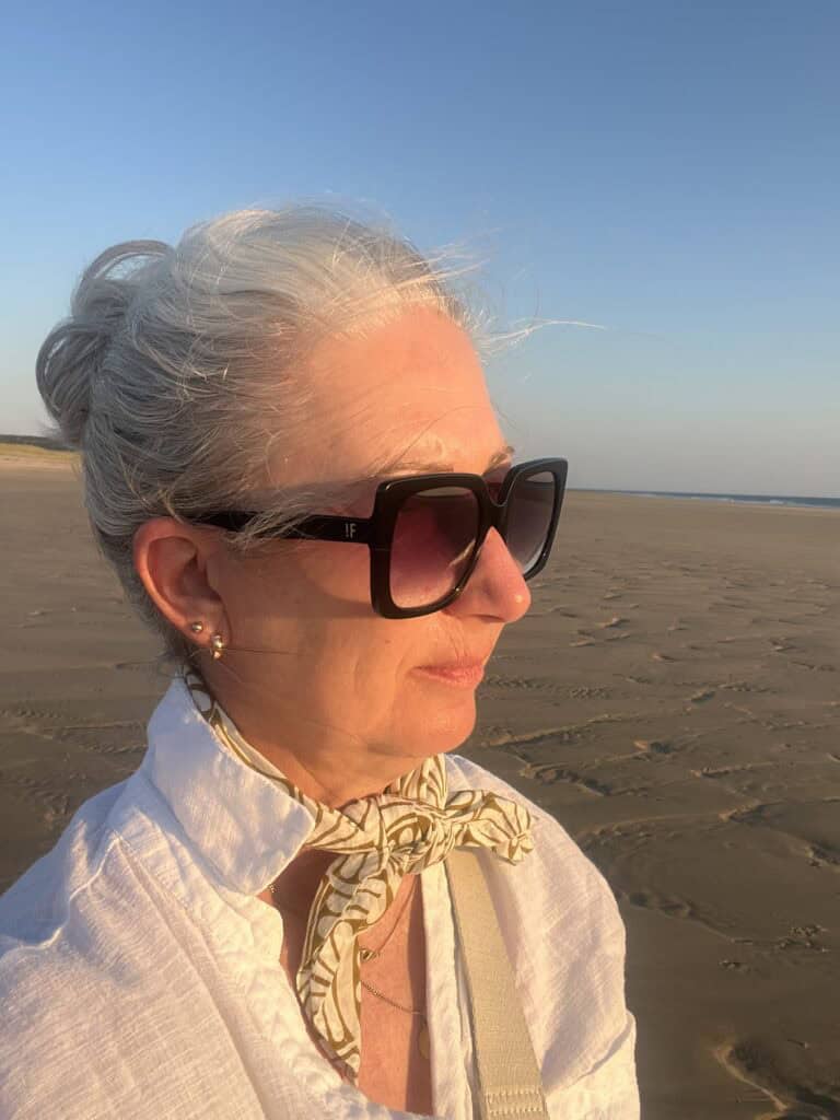 Woman gazing thoughtfully across the beach – a quiet image for self-love and staying true to yourself